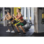 Two,Smiling,Athletic,Girls,Are,Squatting,Synchronously,With,Outfit,In